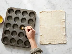 Greasing a mini muffin pan for cranberry brie bites