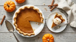 Pumpkin sugar pie made from a fresh pie pumpkin with one slice cut out, whipped cream and small sugar pumpkins