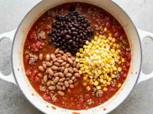 Black beans, pinto beans and corn added to taco soup in a Dutch oven